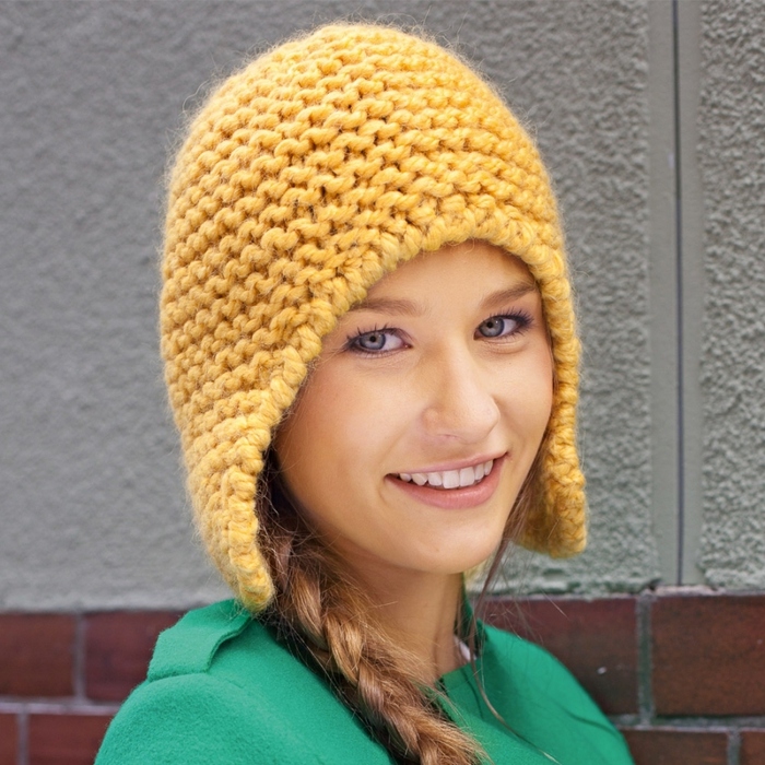 Оригинальная шапка-шлем из толстой пряжи платочным узором на девушке