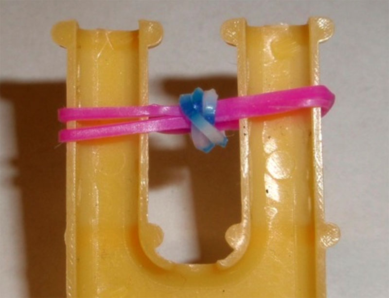 С правой стороны крючком снять синюю деталь и переместить её в центр рогатки