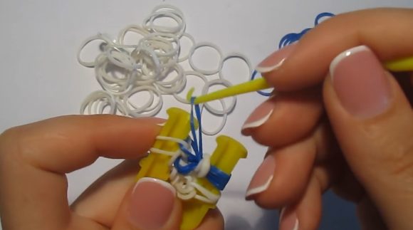 Плетение браслета из синих и белых резинок на рогатке